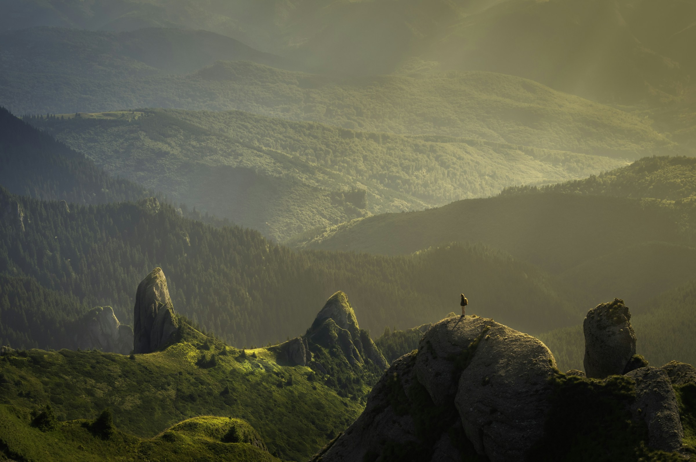 A hiker on a rocky ridge above a green valley